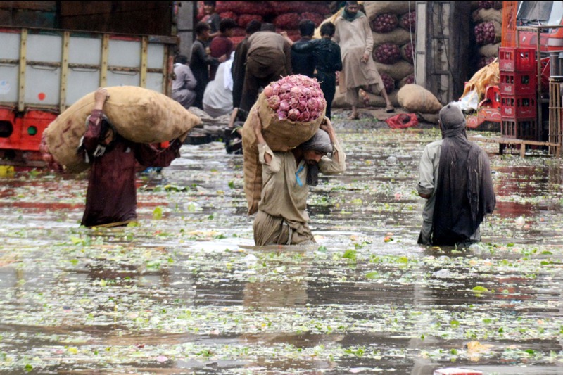 巴基斯坦第二大城拉合爾本月初遇大雨多處積水，工人扛著洋蔥涉水而過。新華社
