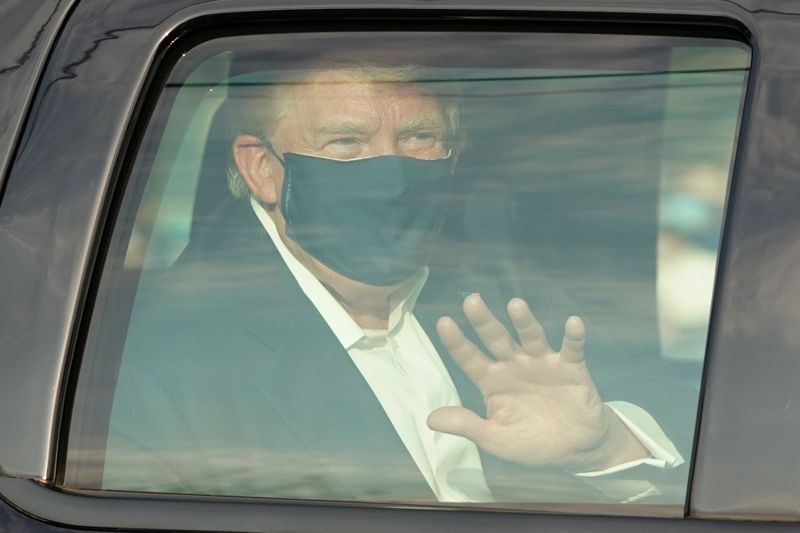 美國總統川普4日短暫離開醫院，坐在車內向守在醫院外的支持者揮手致意。法新社