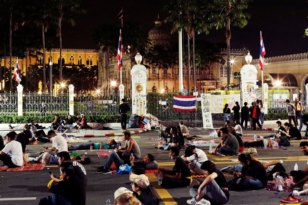 14日晚，儘管略顯疲態但仍守在政府大樓外的示威者。 圖／路透社