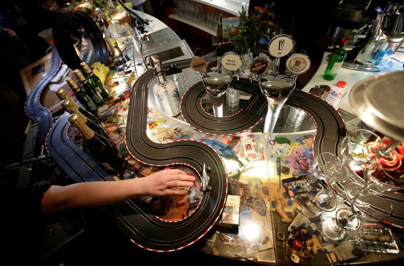 捷克布拉格一間小餐館員工真的在店內吧檯搭起電動玩具車賽道，開始玩玩具車。（路透）