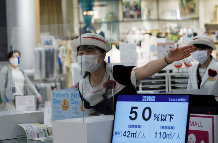 日本一家超市賣場工作人員在戴口罩與加裝隔板的多重防護下，服務顧客。（圖／路透）