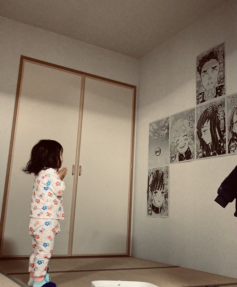 女孩对墙上鬼灭之刃的海报膜拜。 图／取自Twitter