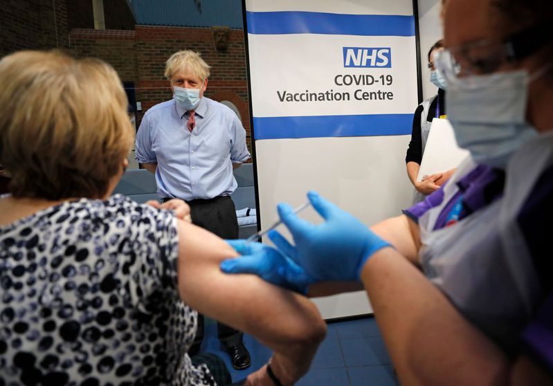 專家認為新冠疫苗對新變種病毒株仍有效，圖為英相強生日前在倫敦一家醫院疫苗接種中心內觀看民眾接種疫苗。法新社