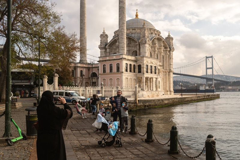 外籍遊客六日和伊斯坦堡的奧塔科伊清真寺合照，土國警方的車則停在一旁巡視有無違規民眾。紐約時報