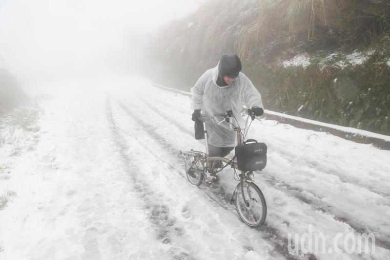 陽明山凌晨開始下雪，吸引民眾上山。有民眾牽著自行車走到大屯山助航站賞雪。記者蘇健忠／攝影