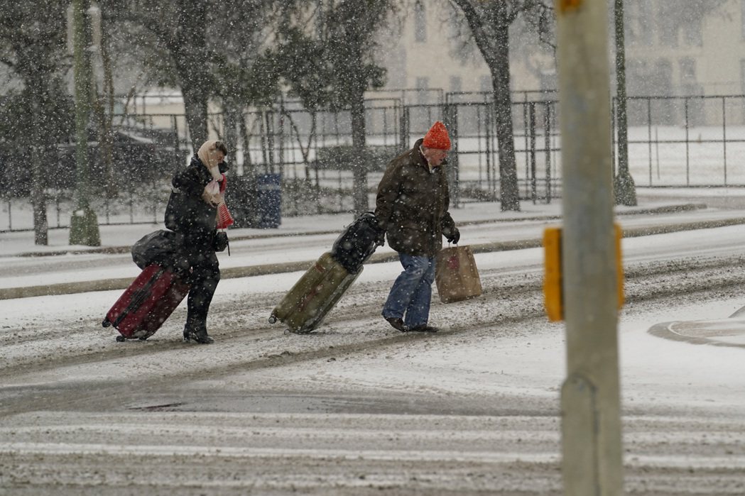 德州居民拖著行李在雪中行走。（美聯社）