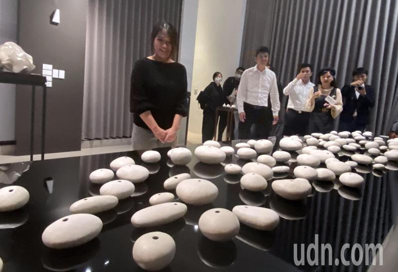 藝術家邱俞鳳（左）介紹，作品「「卵石」看似一顆顆河床上的卵石，其實是以白瓷土手捏而成。記者趙容萱／攝影