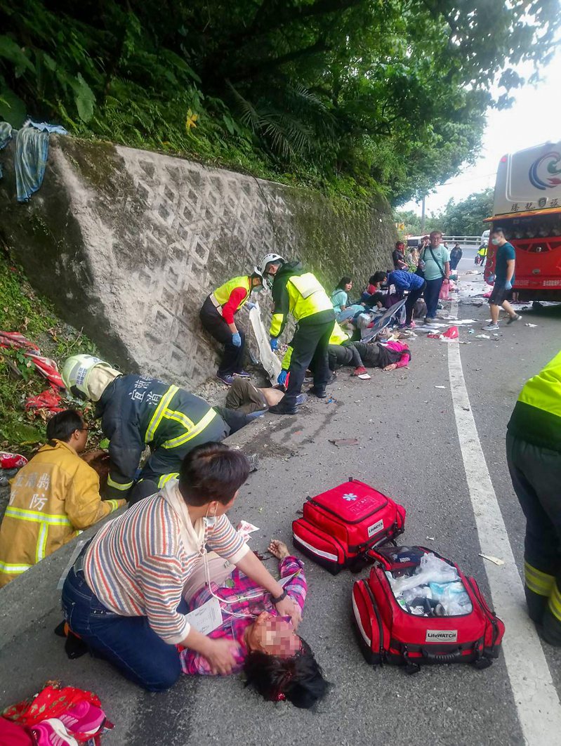 蘇花公路昨天發生遊覽車撞山壁的事故，造成六死卅九傷，消防隊員與民眾協助傷者就醫。圖／讀者提供