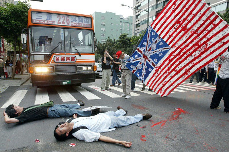 2003年04月12日，部分反戰團體前往美國在台協會抗議美國出兵伊拉克，由於2名演出行動劇的抗議人士向美國在台協會與警方丟擲紅色油漆，遭警方以現行犯短暫收押，2位抗議人士躺在信義路上阻擋交通以示抗議。圖／聯合報系資料照片