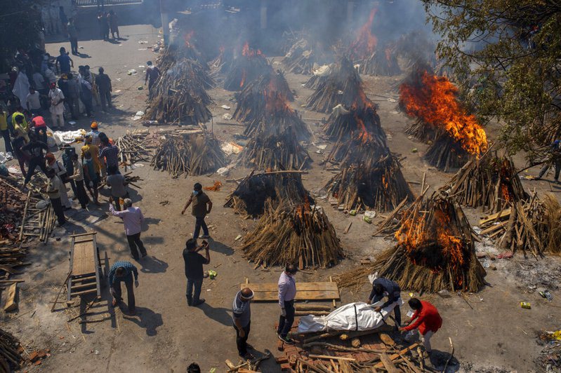 圖為印度新德里在一處廣場上，焚燒因新冠肺炎死亡的罹難者屍體。美聯社