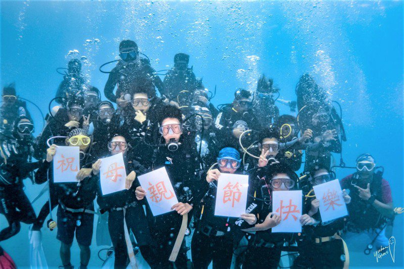 屏東墾丁國小畢業生在台灣潛水公司教練協助下完成難忘的海中畢業典禮，並以預做的標語在海底祝母親節快樂。圖／台灣潛水提供