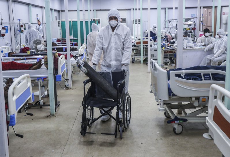印度一所医院的医事人员正使用轮椅运送氧气瓶。 美联社(photo:UDN)