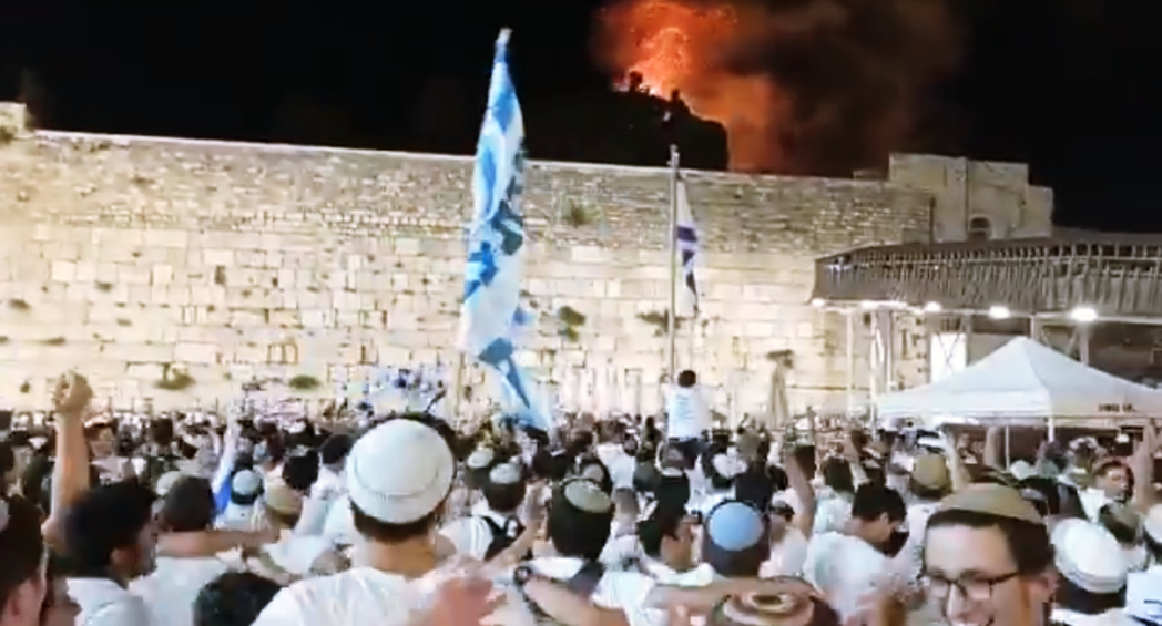 耶路撒冷日大遊行後，在哭牆唱歌跳舞的猶太保守派團體；背後燃燒中的山頭，是剛被以色...