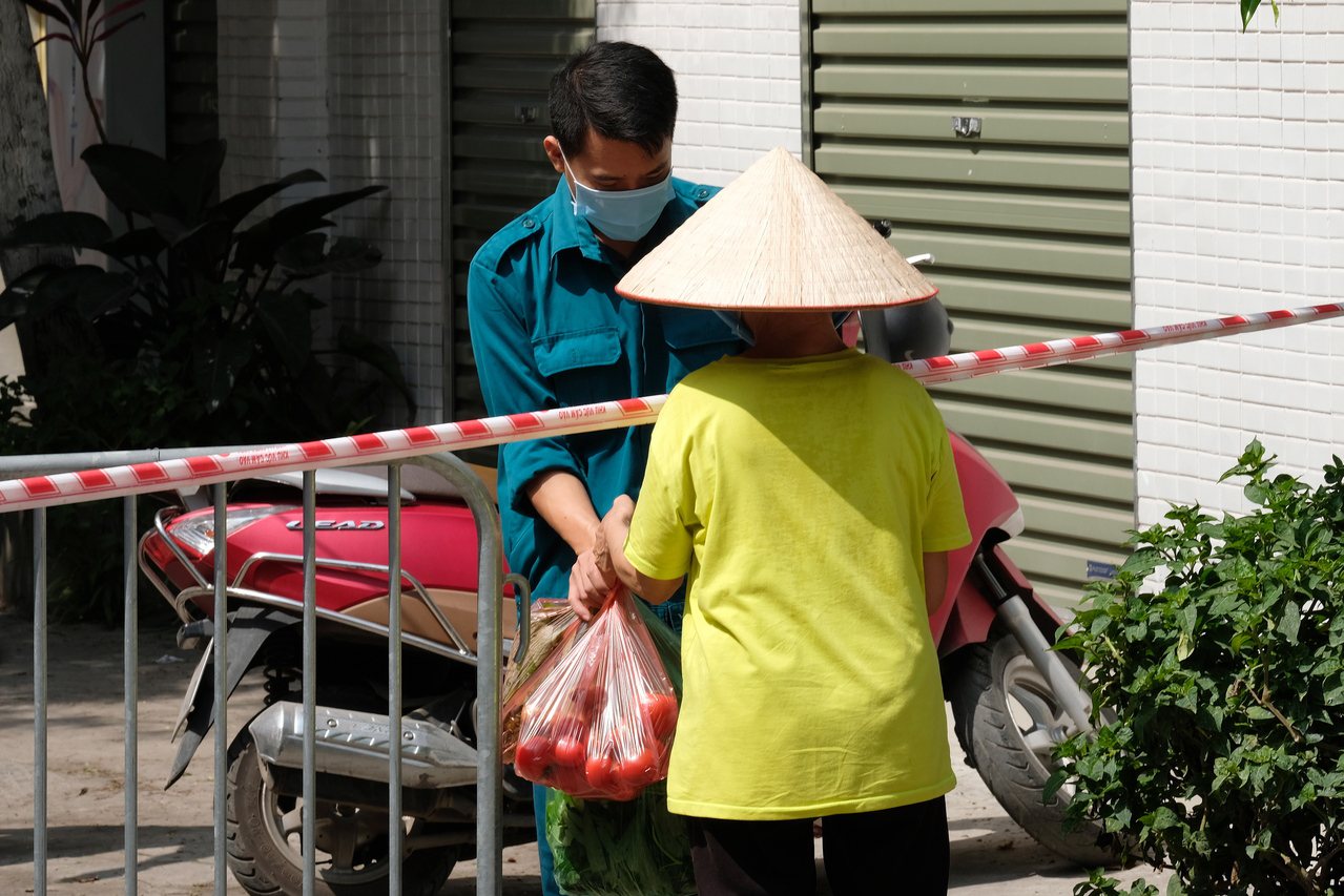 越南首都河內一名男子26日在封鎖區內領取食物。（歐新社）