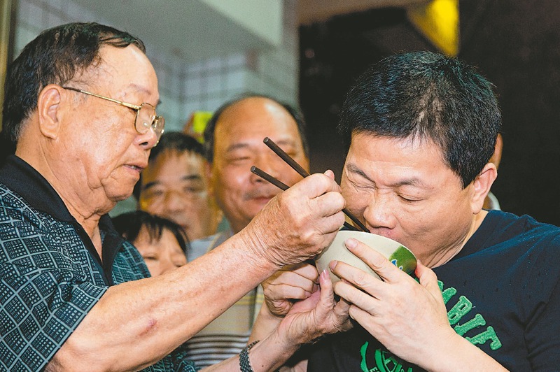 前立委顏清標（右）2014年6月6日假釋出獄，顏的爸爸（左）親自餵吃豬腳，希望能去除霉運。圖／聯合報系資料照片