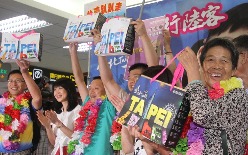 2011年陸客自由行首日，台北市觀光傳播局送給第一批陸客伴手禮包括鳳梨酥、牛肉乾、溫泉券等，陸客高舉禮物感謝。圖／聯合報系資料照片