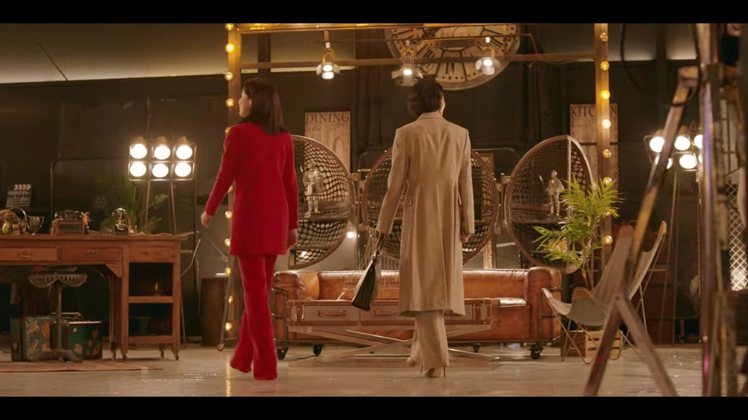 李寶英換上Saint Laurent的紅色高領洋裝式褲裝，同樣是整身同色系的兩件式搭配，並完整複製當初此系列發表時模特兒用金色項鍊點綴的穿法，復古俐落又帶一絲貴氣。圖／摘自Netflix