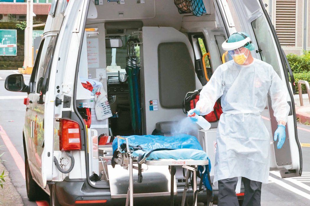 救護車上的救護技術員每天全副武裝進出急診室，出完任務固定消毒救護車上的擔架床。記者蘇健忠／攝影