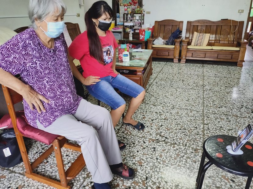 85歲的阿伸阿嬤，在「外籍看護」神隊友協助下與弘道社工遠距進行視訊運動。 圖／弘...