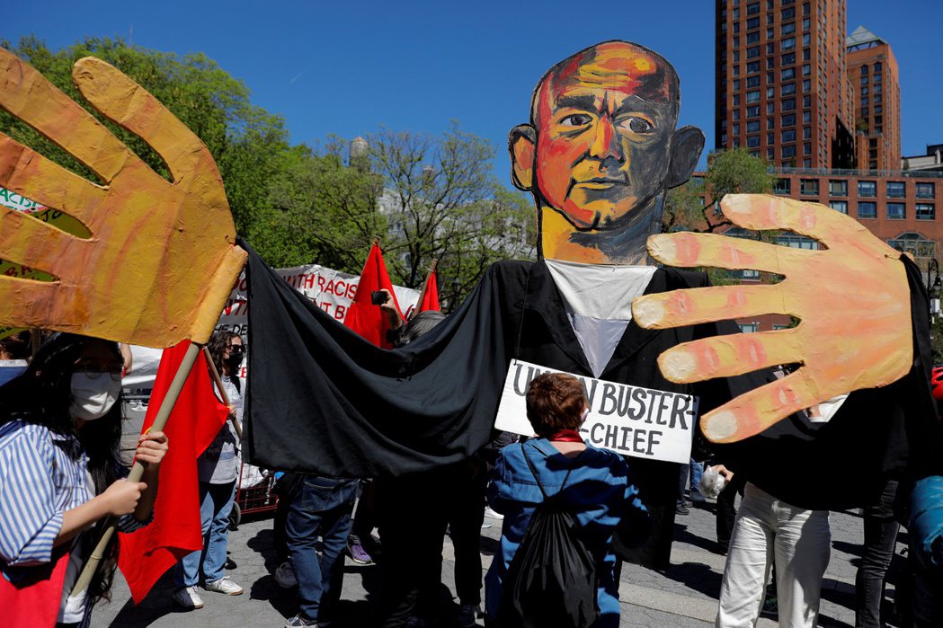 圖為在5月1日的勞動節遊行中，民眾舉著在疫情間發大財的貝佐斯肖像。過去一年，亞馬...