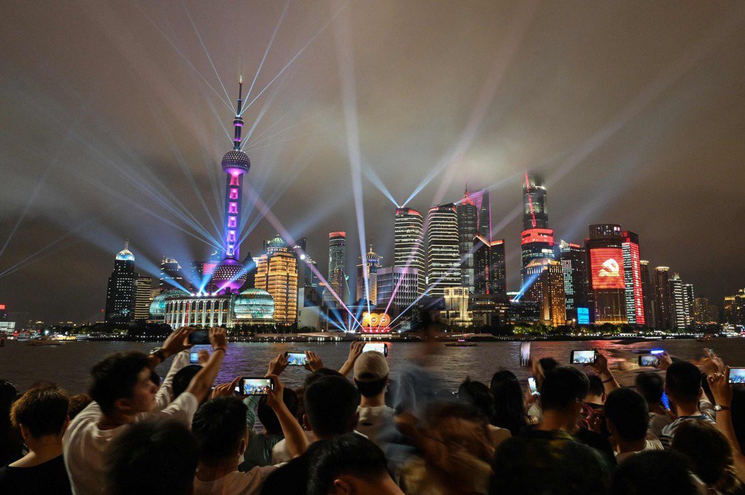 7月1日中共建黨100週年之際，民眾在上海觀看五光十射的燈光秀。 圖／法新社 ...
