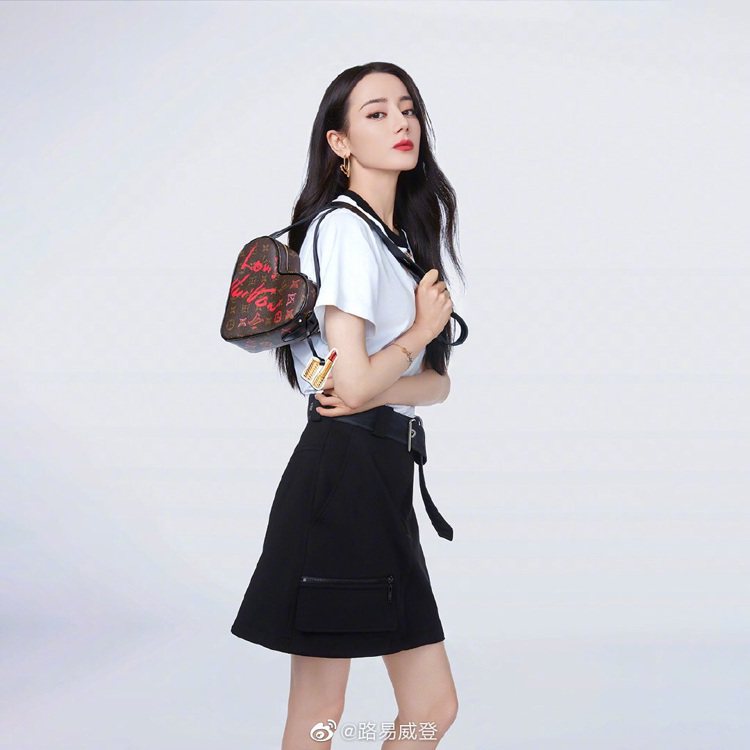 迪麗熱巴拎著New Wave Heart Bag，搭襯白上衣和短裙根本就是學生造型。圖／取自微博