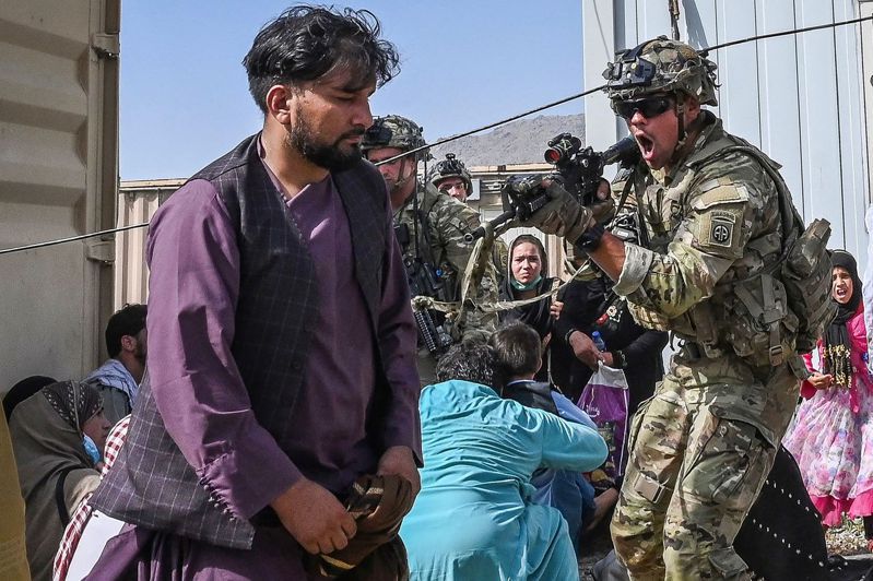 一名把守喀布尔机场的美军（右）十六日举枪喝斥阿富汗民众。众多阿富汗人涌入机场，希望搭上飞机逃离。（法新社）(photo:UDN)