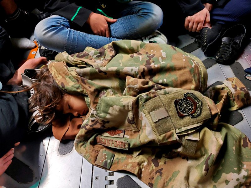 一架美军运输机十八日飞离喀布尔，一名孩童睡在机舱地板，身上盖着机组员的制服取暖。（路透）(photo:UDN)
