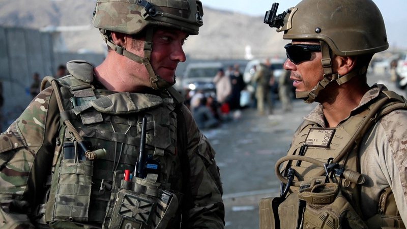 一名英國軍人（左）22日在喀布爾機場與一名美國軍人（右）交談。法新社