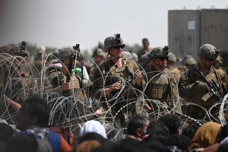 美國官兵20日在阿富汗首都喀布爾機場軍事區附近蛇籠駐守，現場聚集了想逃出阿富汗的民眾。法新社