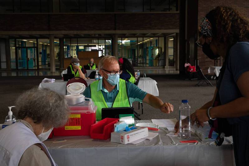 美公卫官员认为加强针接种间隔不应缩短，图为24日一位迈阿密民众在接种加强针前秀出她的疫苗接种卡。法新社(photo:UDN)
