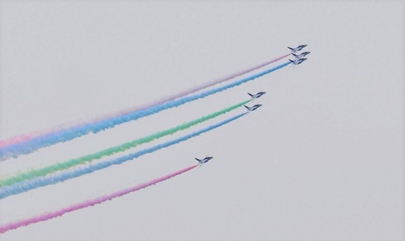 日本航空自衛隊在24日東京帕運開幕當天舉行飛行表演「藍色衝擊波」，6架飛機在東京上空噴3色彩煙表演，另有3架預備機將降落時還噴彩煙，造成約300輛車子染色。(中央社)