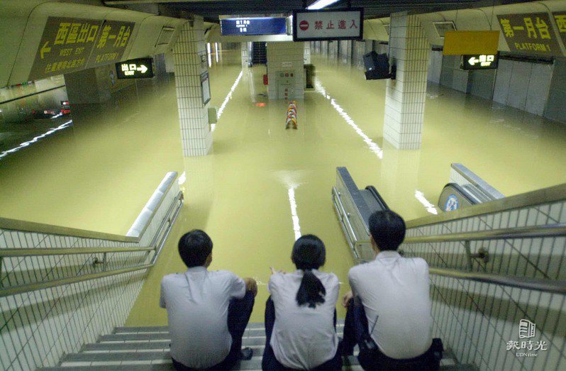 臺北車站在納莉颱風的肆虐下也無法逃離被大水淹沒的命運，整個地下車站軌道與月台全都浸泡在大水中，而節節上升的水位更令駐守在該區的鐵路警察不敢大意，只得坐在階梯上盯著水位。日期：2001/9/17．攝影：杜建重．來源：聯合報
