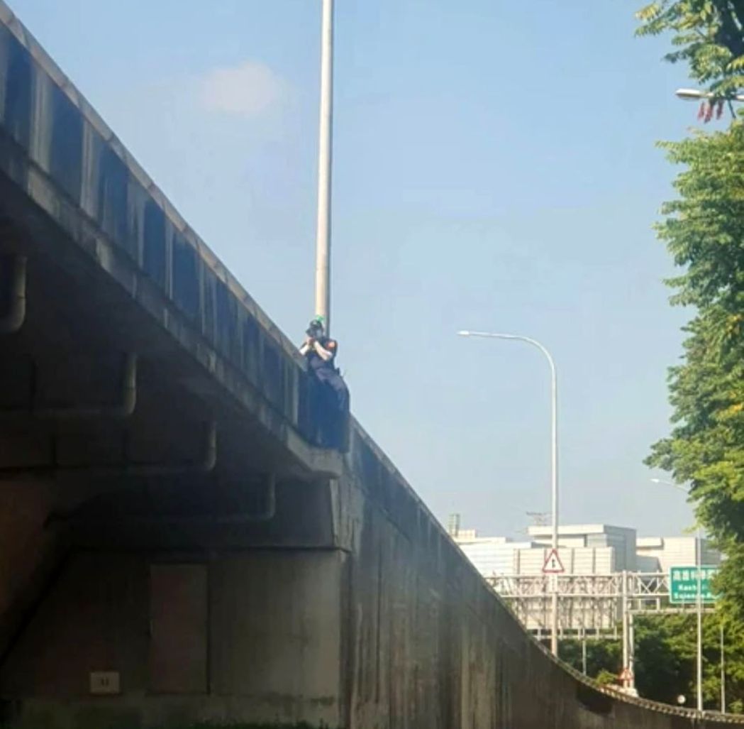保二總隊警員跨坐高架橋護欄測速拍照，取締超速。圖／截自臉書爆料公社二館