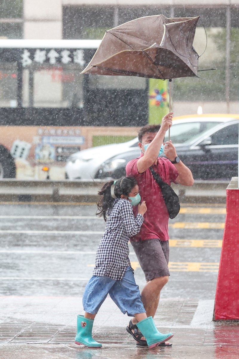 璨樹颱風來襲，為東半部、北部帶來強風豪雨，路人行人的傘都被吹歪了。記者葉信菉／攝影
