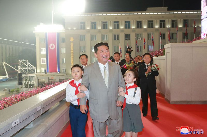 北韓領導人金正恩9日穿著灰色西裝，繫閃亮的白色領帶在建政73周年閱兵式亮相，雙手分別被一名男童和女童牽著。法新社