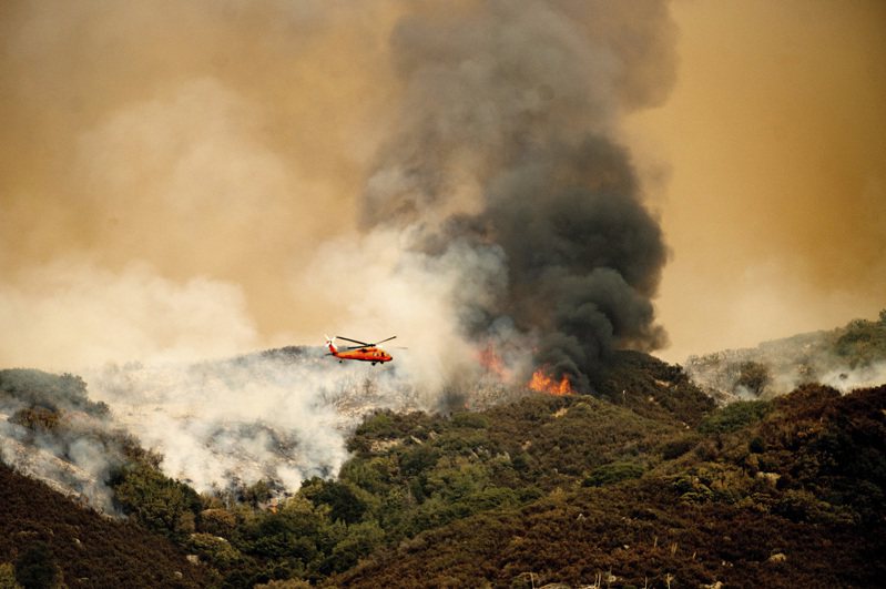 KNP複合山火步步逼近美國加州紅杉國家公園巨杉森林，一架直升機15日正準備灑水遏制火勢。（美聯社）