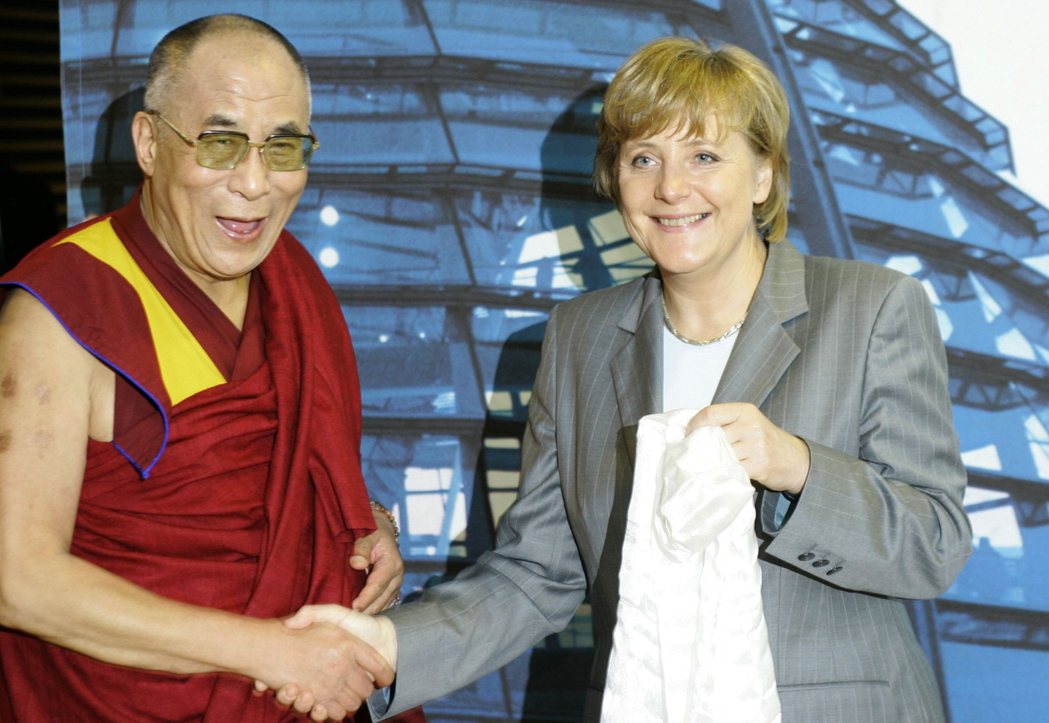 圖為2007年，梅克爾在德國迎接達賴喇嘛，並收下達賴贈與、象徵祝福敬意的哈達。 ...