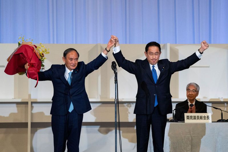 日本前外相岸田文雄（右）廿九日當選自民黨黨魁，和即將離任的首相菅義偉（左）一同慶祝。（路透）