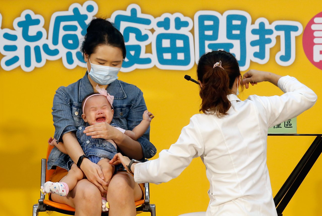 衛福部疾病管制署舉行「守護我們所愛的人」公費流感疫苗開打記者會，邀請一對父母帶著雙胞胎幼兒到現場接種，小女嬰打針後當場大哭。記者鄭超文／攝影