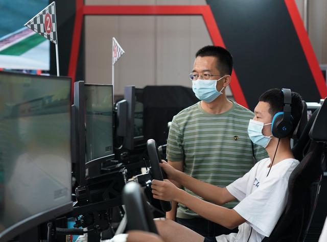 參觀2021北京服貿會的民眾，在體育服務展館內體驗賽車模擬器。（圖／新華社）
