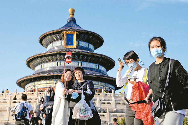 圖為中國長假最後一天，遊客戴著口罩在北京天壇自拍。美聯社