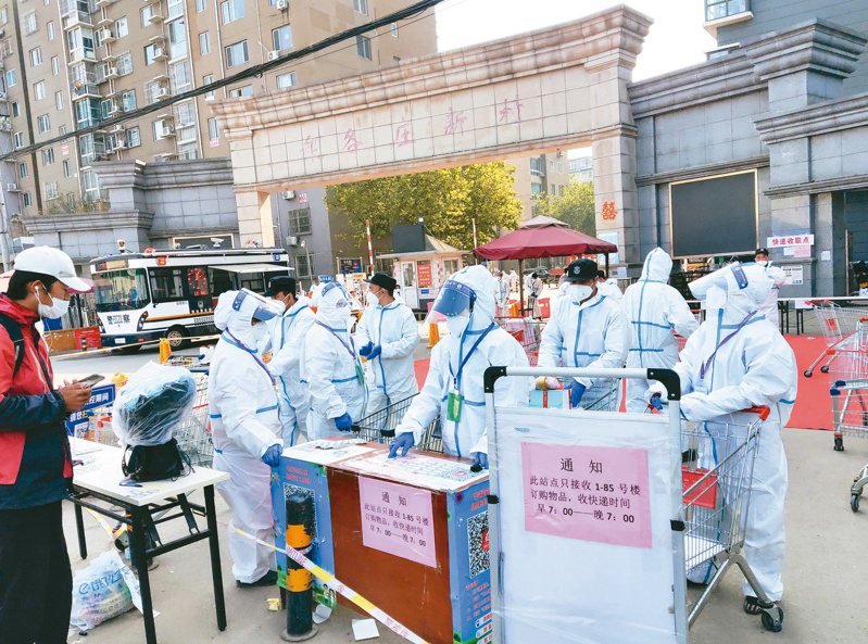 北京防疫人員昨在昌平區一社區門口，登記接收居民購買的各類物品，該區二十三日調整為高風險地區。（中新社）