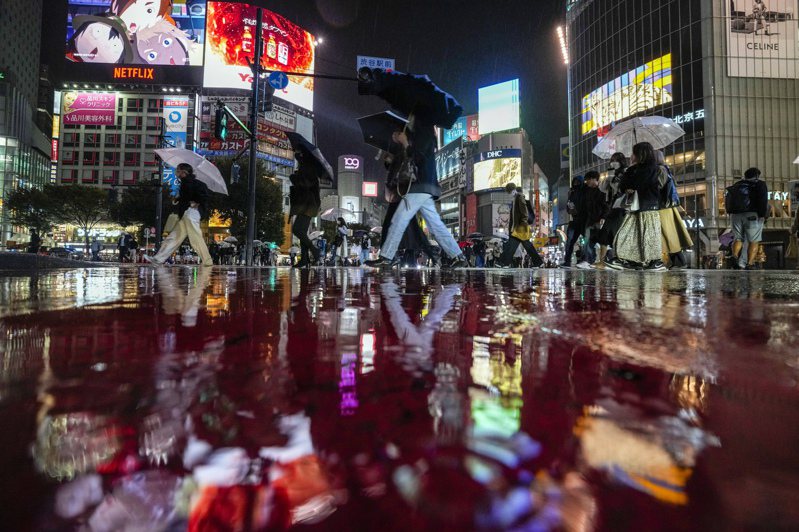 日本東京民眾上月25日晚間戴口罩經過當地著名購物娛樂區澀谷。美聯社