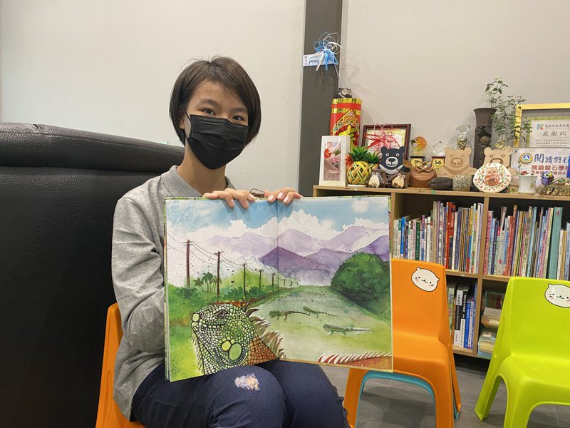 餉潭國小6年學生潘宥琳開心地秀出，繪本「綠野蜥蹤」她畫的這一頁，綠鬣蜥過馬路。記者劉星君／攝影