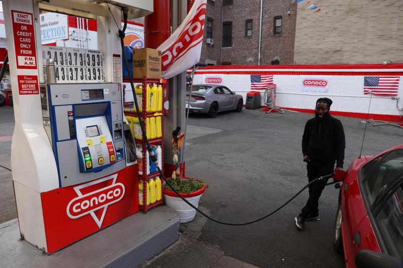 美國總統拜登廿三日宣布釋出五千萬桶戰備儲油以平抑油價。圖為紐約一名男子在加油站加油，目前美國汽油價格是一年前的兩倍。圖／路透社