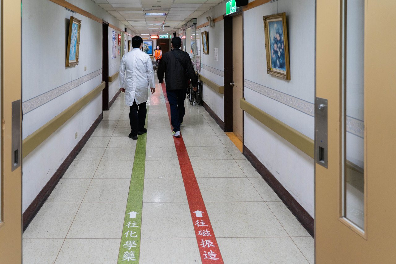 肺癌病友黃琪証與主治醫師羅永鴻並肩走在台北榮總地下室腫瘤醫學部的長廊。
