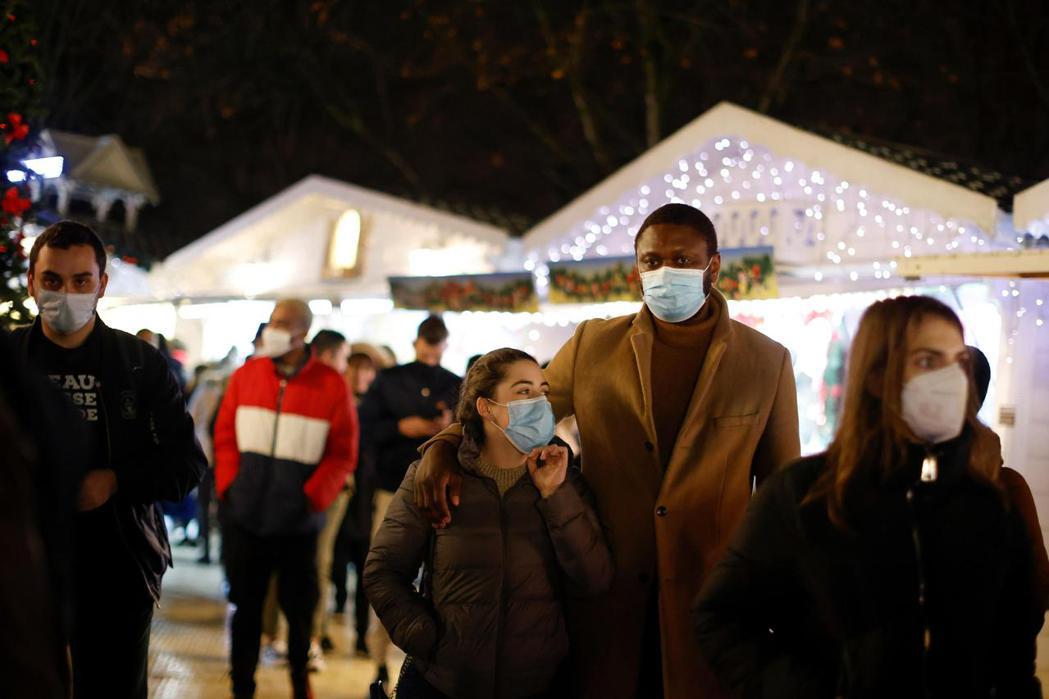 法國巴黎的行人戴著口罩經過聖誕市集，法國政府坦承，危險的Omicron病毒株可能...