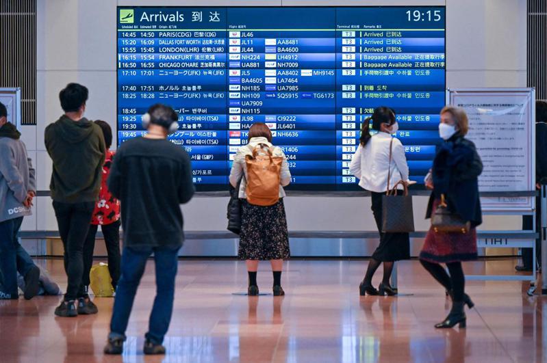 日本民眾1日在東京羽田國際機場航班時刻表前觀看航班資訊。法新社