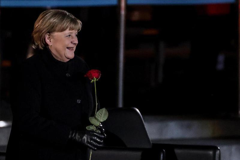 梅克爾的歌單令外界大感意外，讓德國人留下深刻印象。圖為她手持玫瑰，笑著聆聽軍樂隊演奏。 歐新社